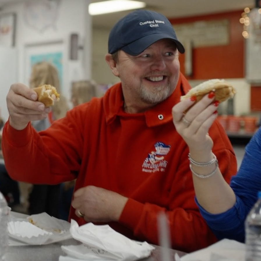 A person holding up a hot dog bun at Custard Stand Chili