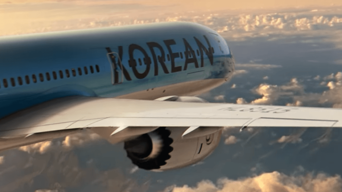 A close-up, aerial view of a light blue Korean Air passenger jet flying above a thick layer of clouds